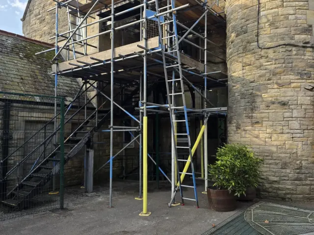 Scaffold tower against a stone church building